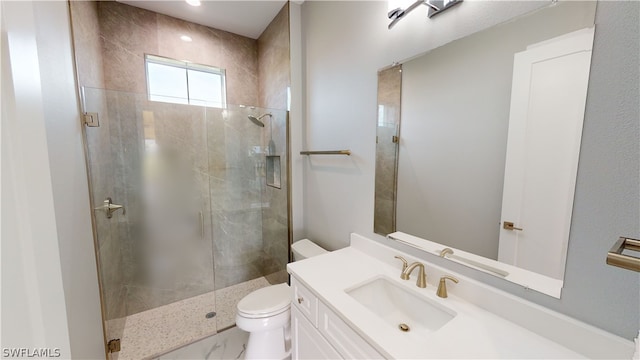 bathroom featuring toilet, a shower with door, and vanity