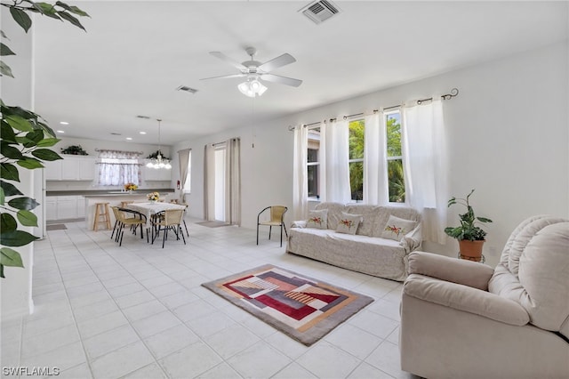 living room with light tile floors and ceiling fan with notable chandelier