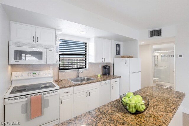 kitchen with backsplash, white appliances, sink, white cabinets, and dark stone counters