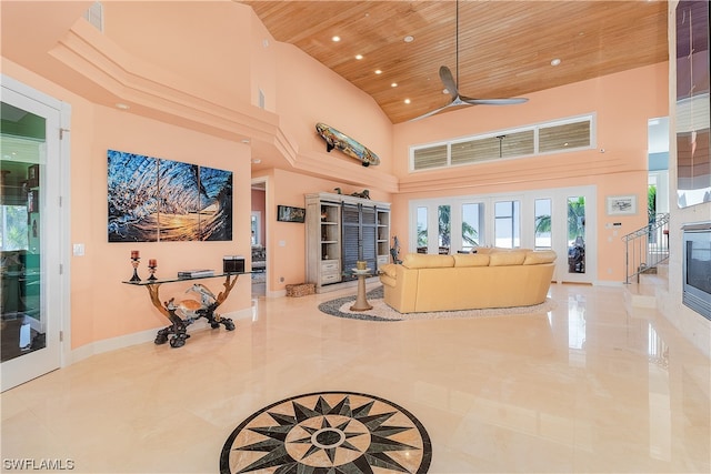 living room featuring ceiling fan, wooden ceiling, and a towering ceiling