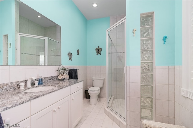 bathroom with vanity, toilet, tile walls, and walk in shower