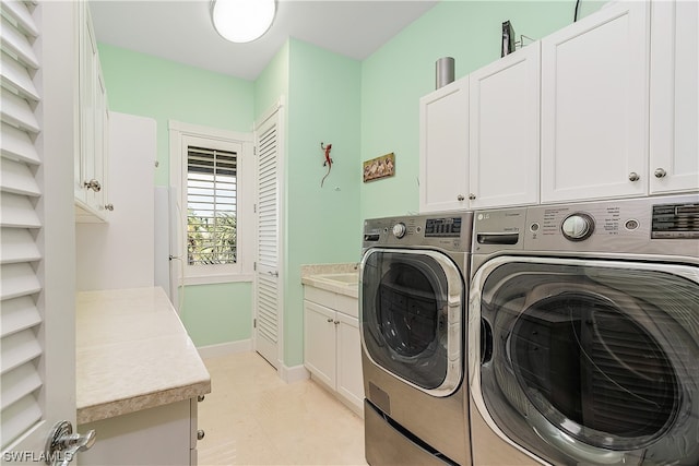 clothes washing area featuring cabinets, washing machine and clothes dryer, and light tile patterned flooring