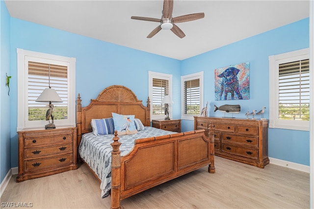 bedroom featuring light hardwood / wood-style flooring, ceiling fan, and multiple windows