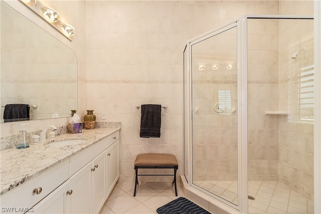 bathroom with vanity, a shower with shower door, and tile walls