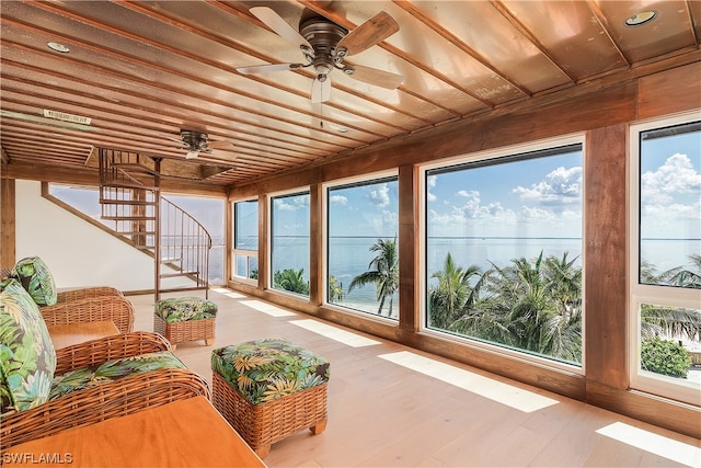 sunroom / solarium with a water view and ceiling fan