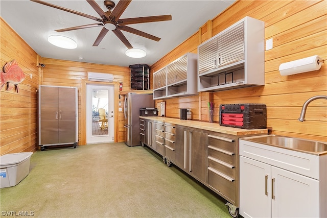 kitchen featuring white cabinets, ceiling fan, a wall unit AC, and wooden walls