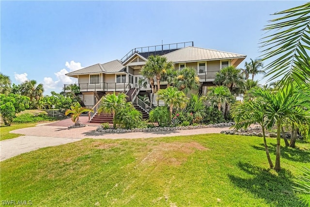 211 Kingfisher Dr, Captiva, FL 33924 - raised beach house with a front lawn, metal roof, decorative driveway, and stairs