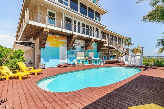 view of swimming pool with a wooden deck and a grill