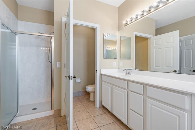 bathroom featuring tile patterned floors, toilet, a shower with shower door, and vanity