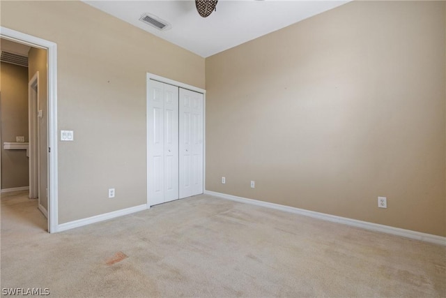 unfurnished bedroom with light colored carpet and a closet