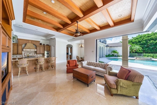 tiled living room featuring beam ceiling, coffered ceiling, ceiling fan with notable chandelier, and ornamental molding