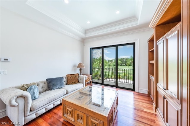 living room with a tray ceiling, hardwood / wood-style flooring, and ornamental molding