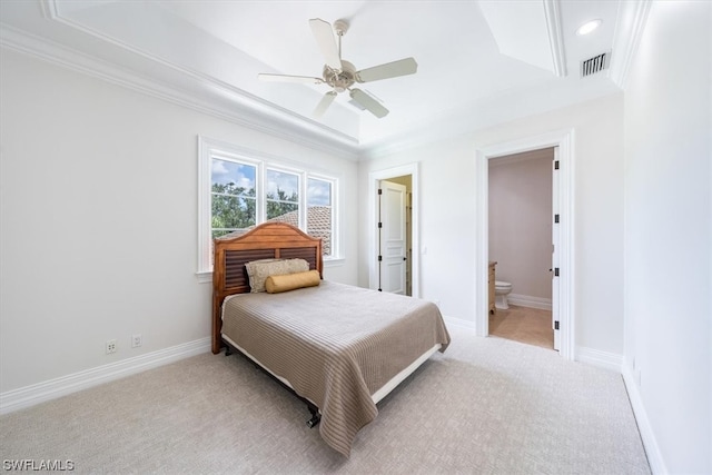 bedroom featuring light colored carpet, a tray ceiling, ceiling fan, ornamental molding, and ensuite bathroom