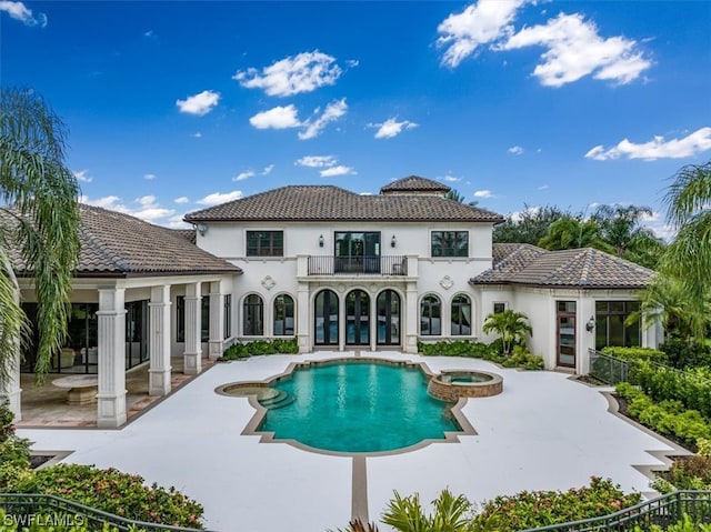 rear view of house featuring a balcony, a pool with hot tub, and a patio area