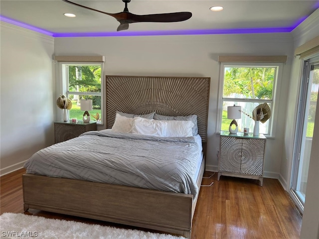 bedroom with ceiling fan, multiple windows, and dark wood-type flooring