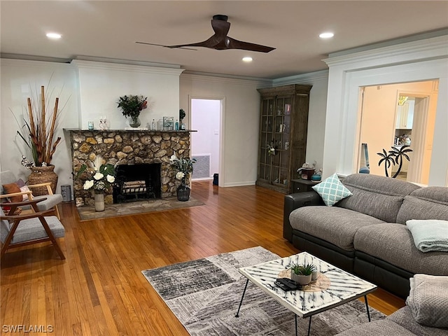 living room with crown molding, a fireplace, ceiling fan, and hardwood / wood-style flooring