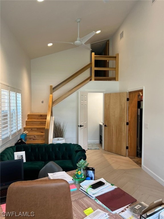 living room with light hardwood / wood-style flooring, a high ceiling, and ceiling fan