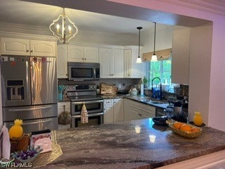 kitchen featuring pendant lighting, white cabinetry, appliances with stainless steel finishes, and a chandelier