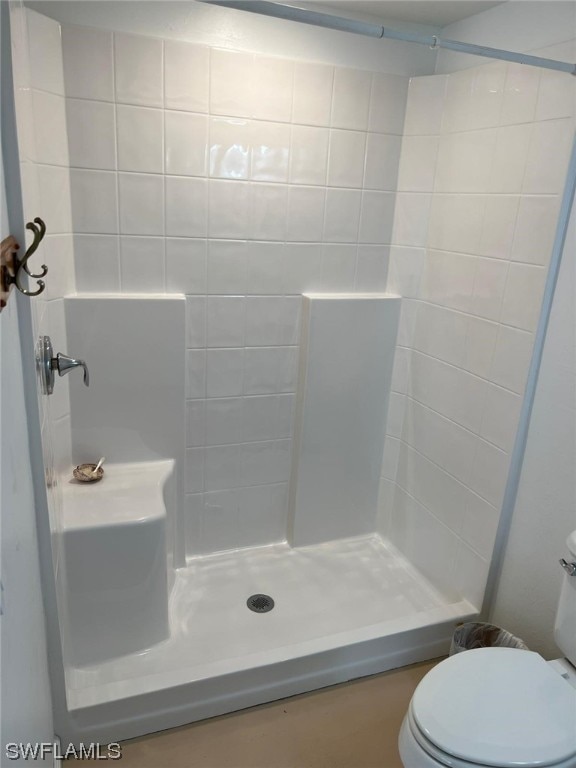 bathroom featuring a tile shower and toilet