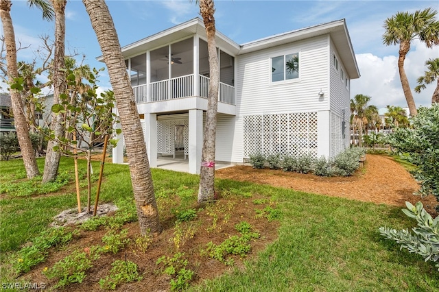 back of property with a lawn, ceiling fan, a sunroom, and a patio