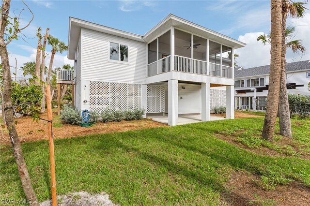 rear view of house with a sunroom, ceiling fan, a yard, and a patio area