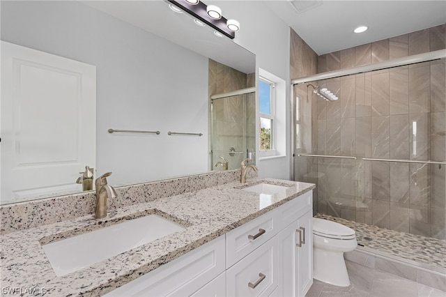 bathroom with tile patterned floors, vanity, toilet, and a shower with door