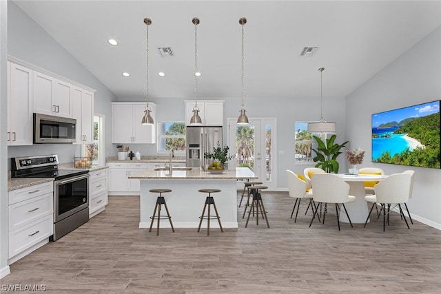 kitchen featuring sink, stainless steel appliances, an island with sink, lofted ceiling, and white cabinets