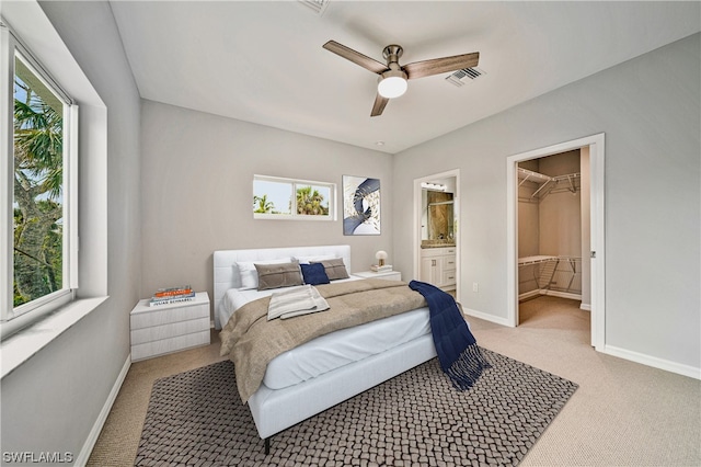 carpeted bedroom featuring ensuite bathroom, a spacious closet, and multiple windows