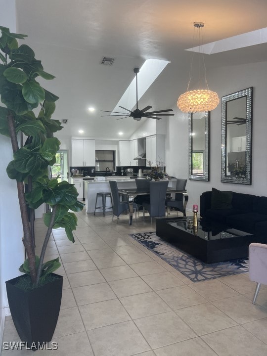 living room featuring a skylight, ceiling fan, plenty of natural light, and light tile patterned flooring