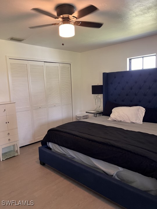 bedroom with ceiling fan, a closet, and light hardwood / wood-style floors