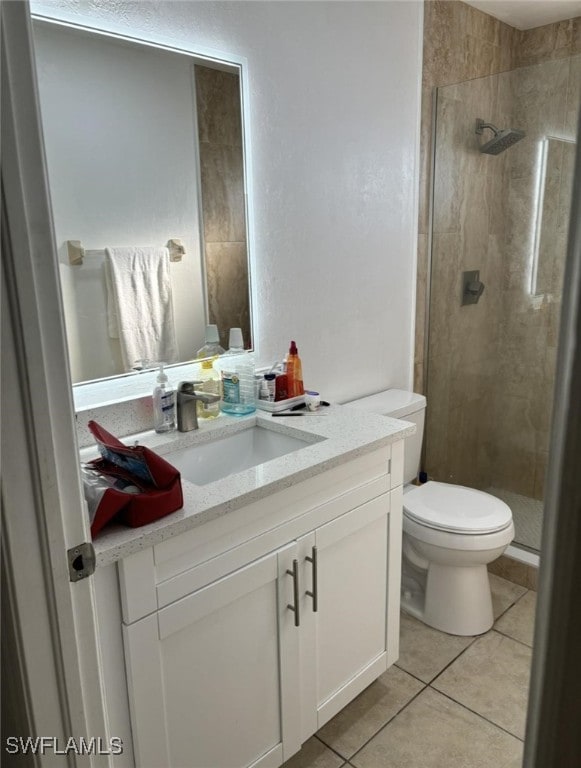 bathroom featuring tiled shower, vanity, toilet, and tile patterned flooring