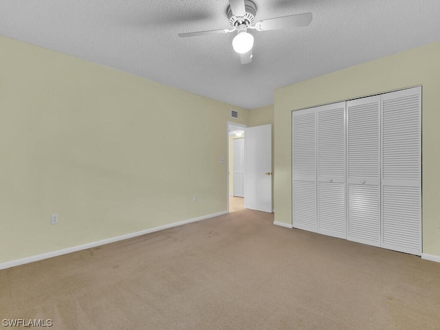 unfurnished bedroom with light carpet, a closet, ceiling fan, and a textured ceiling