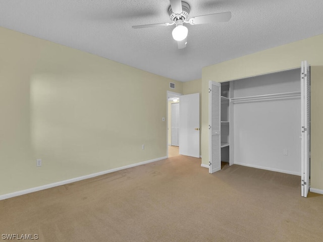 unfurnished bedroom with light colored carpet, a closet, ceiling fan, and a textured ceiling