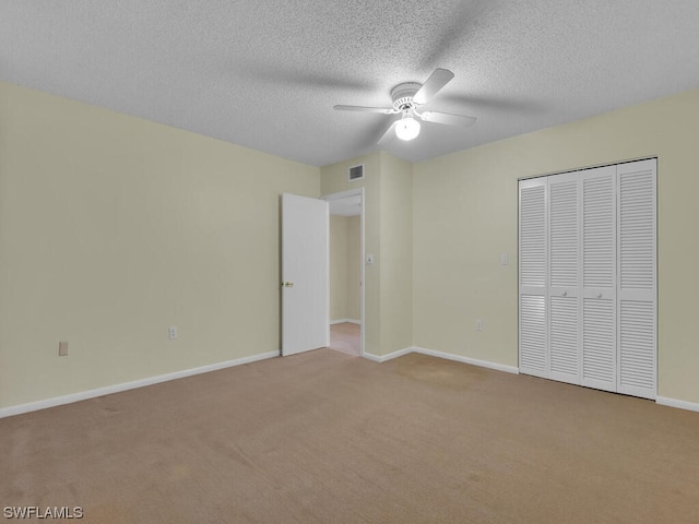 unfurnished bedroom with light carpet, a textured ceiling, a closet, and ceiling fan