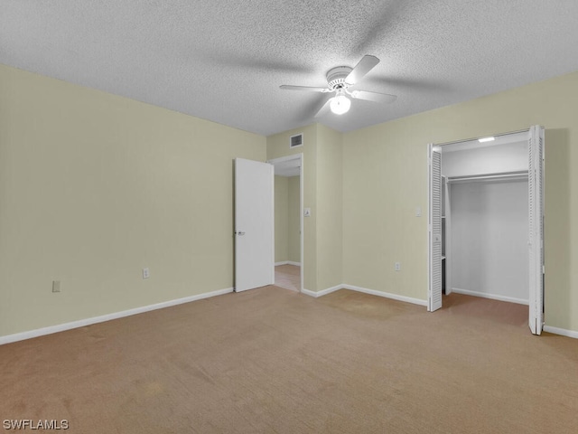 unfurnished bedroom featuring light carpet, a textured ceiling, a closet, and ceiling fan