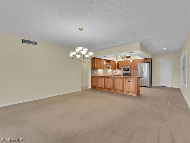 unfurnished living room with a textured ceiling, light colored carpet, sink, and ceiling fan with notable chandelier