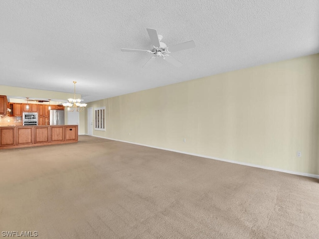 unfurnished living room with a textured ceiling, ceiling fan with notable chandelier, and light colored carpet