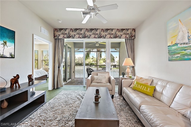 living room with ceiling fan, dark colored carpet, and plenty of natural light