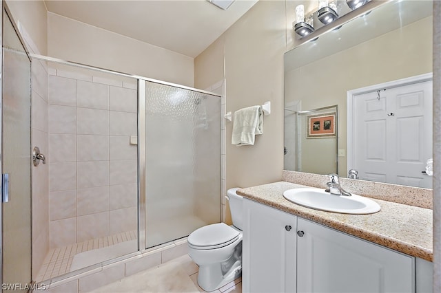 bathroom featuring tile flooring, toilet, a shower with shower door, and vanity with extensive cabinet space