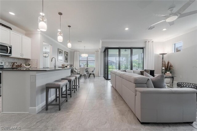 living room featuring ceiling fan, plenty of natural light, and ornamental molding