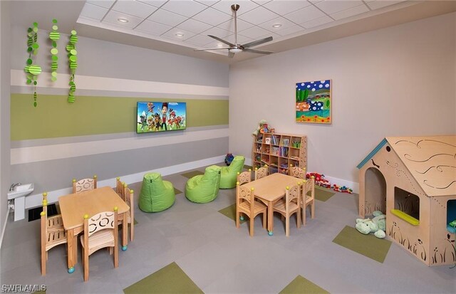 recreation room with a drop ceiling and ceiling fan