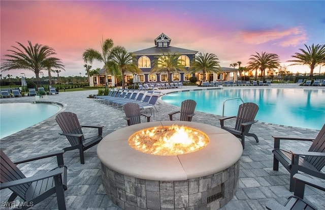 pool at dusk featuring a patio area and an outdoor fire pit