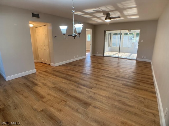 unfurnished dining area with wood-type flooring and ceiling fan with notable chandelier