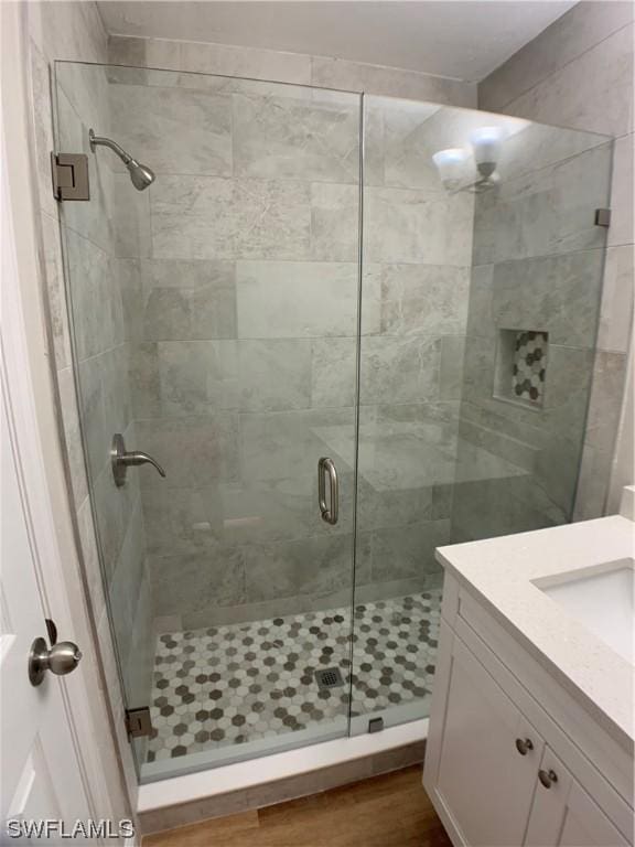 bathroom with hardwood / wood-style floors, vanity, and a shower with shower door