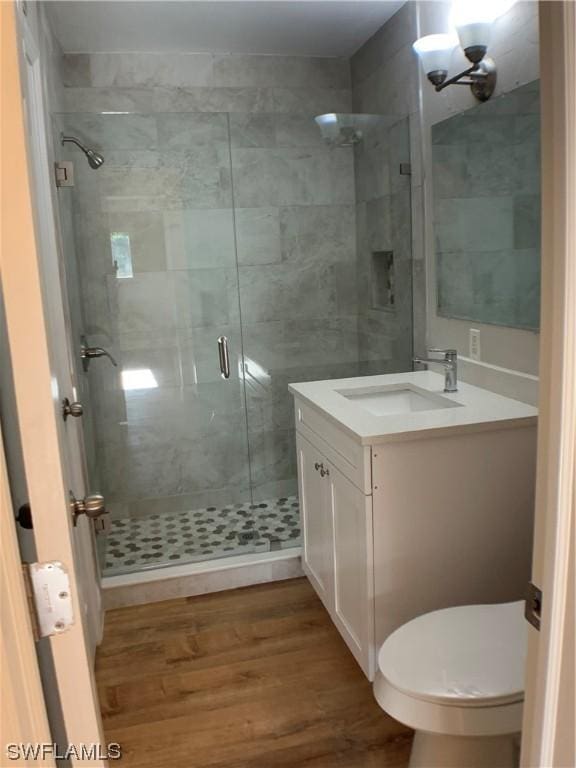 bathroom with toilet, vanity, wood-type flooring, and walk in shower