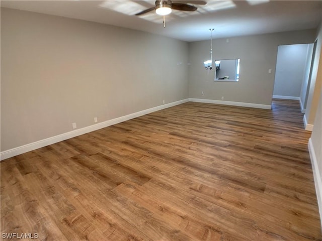 spare room featuring hardwood / wood-style floors and ceiling fan with notable chandelier