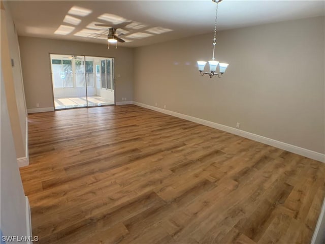 unfurnished room with ceiling fan with notable chandelier and hardwood / wood-style flooring