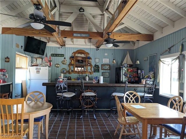 kitchen with ceiling fan, vaulted ceiling with beams, white refrigerator, wood walls, and black refrigerator