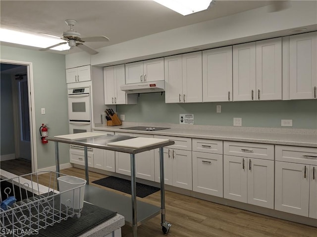 kitchen featuring ceiling fan, light wood-type flooring, black electric cooktop, double oven, and white cabinetry