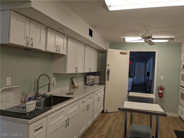 kitchen featuring white cabinets, hardwood / wood-style flooring, ceiling fan, and sink